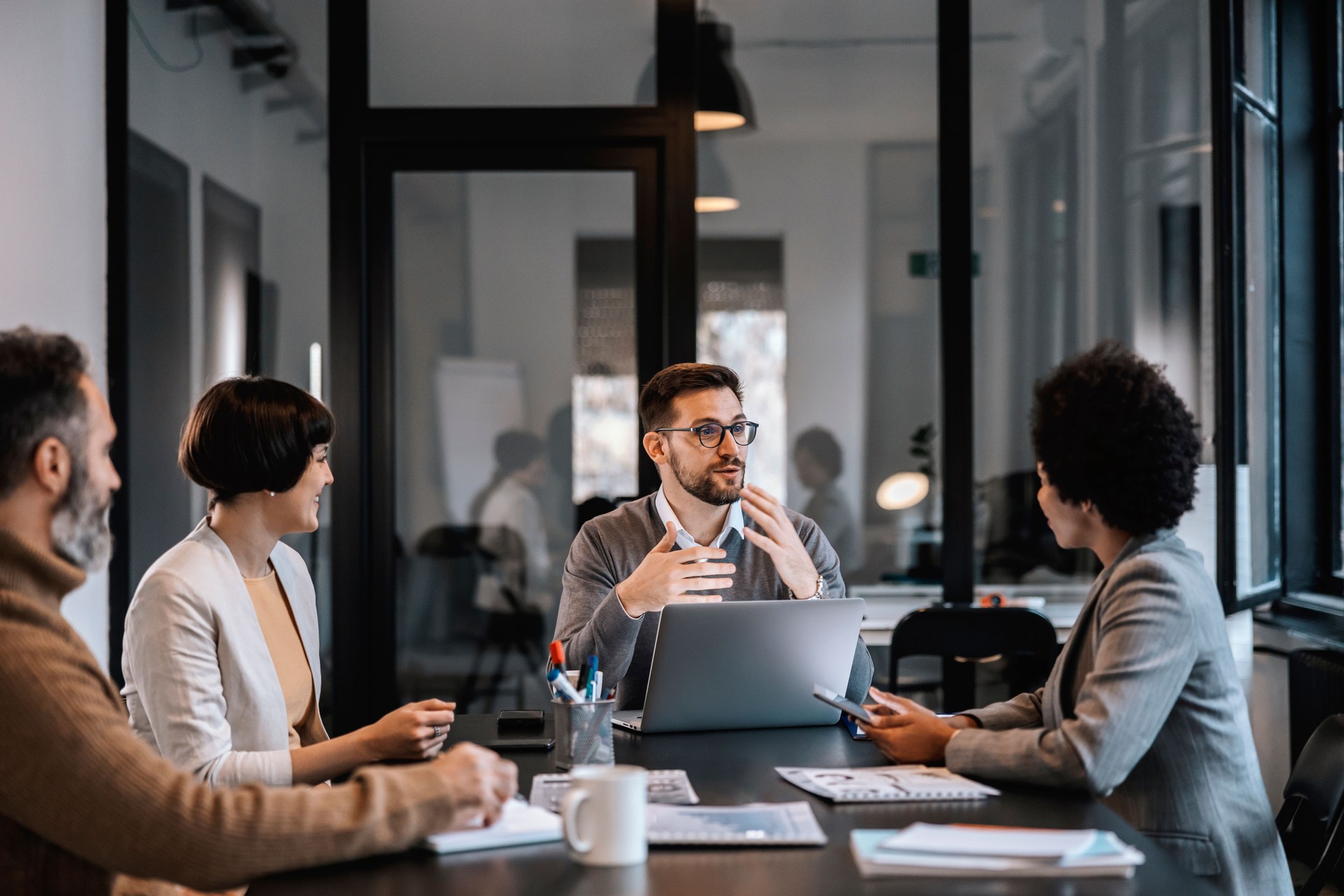 Un mentor dévoué explique aux mentorés l’importance du projet tout en siégeant à la salle de conférence d’une entreprise.