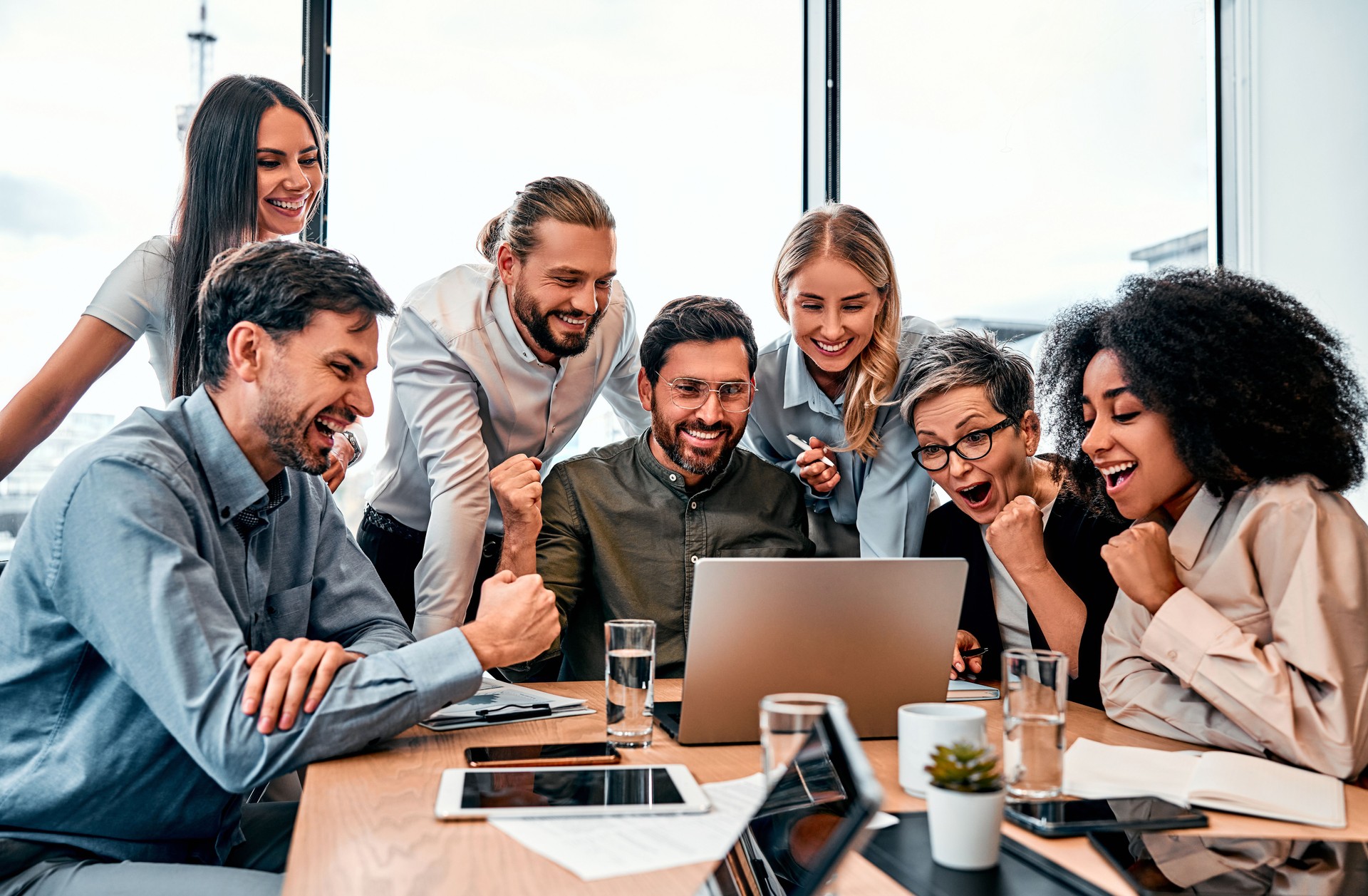 Succès de l’entreprise. Des entrepreneurs multinationaux enthousiastes font le geste gagnant tout en célébrant l’atteinte d’un objectif impressionnant.